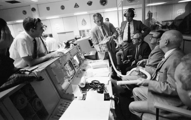 Flight controllers gathered around a console working the problem