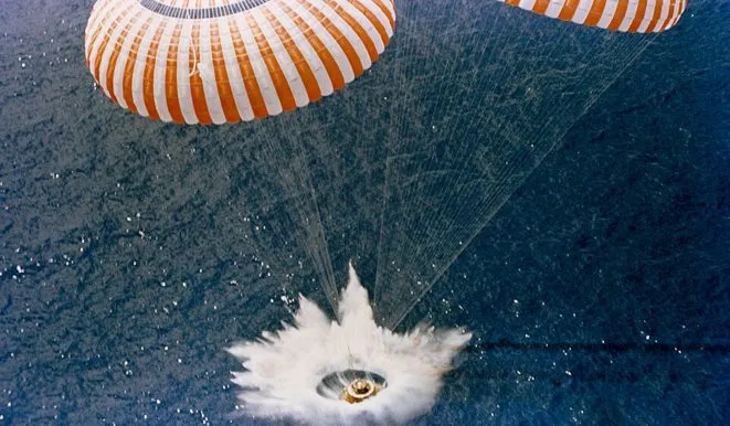 Apollo 13 command module splashing down under parachutes